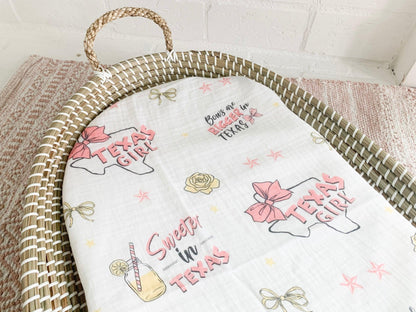 Texas-themed baby girl gift set with muslin swaddle blanket, burp cloth, and bib, featuring pink and white designs.