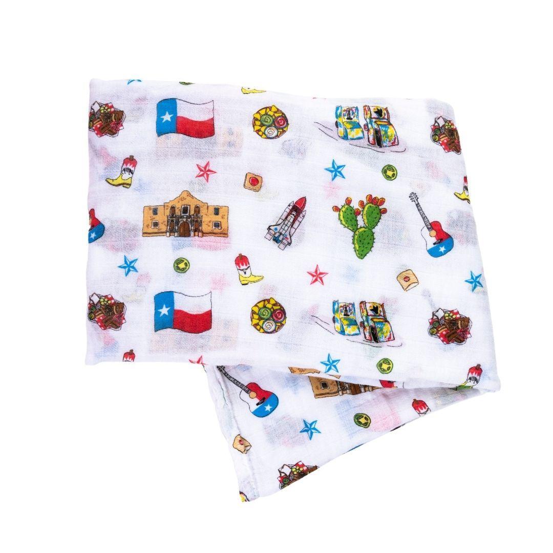 Texas-themed baby gift set with muslin swaddle blanket and burp cloth, featuring state icons and landmarks.