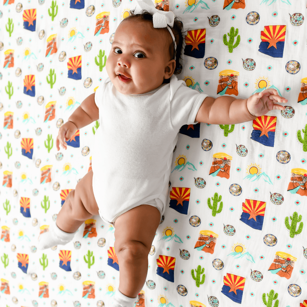 Gift set with Arizona-themed muslin swaddle blanket and burp cloth, featuring cacti and desert motifs.