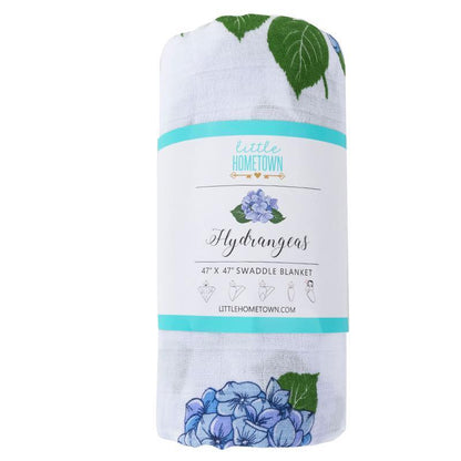 Soft muslin baby swaddle blanket with delicate hydrangea print in pastel blues and greens, folded neatly.