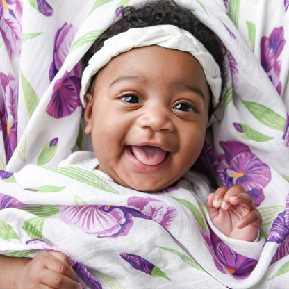 Soft muslin swaddle blanket with pastel iris flower pattern, neatly folded on a white background.