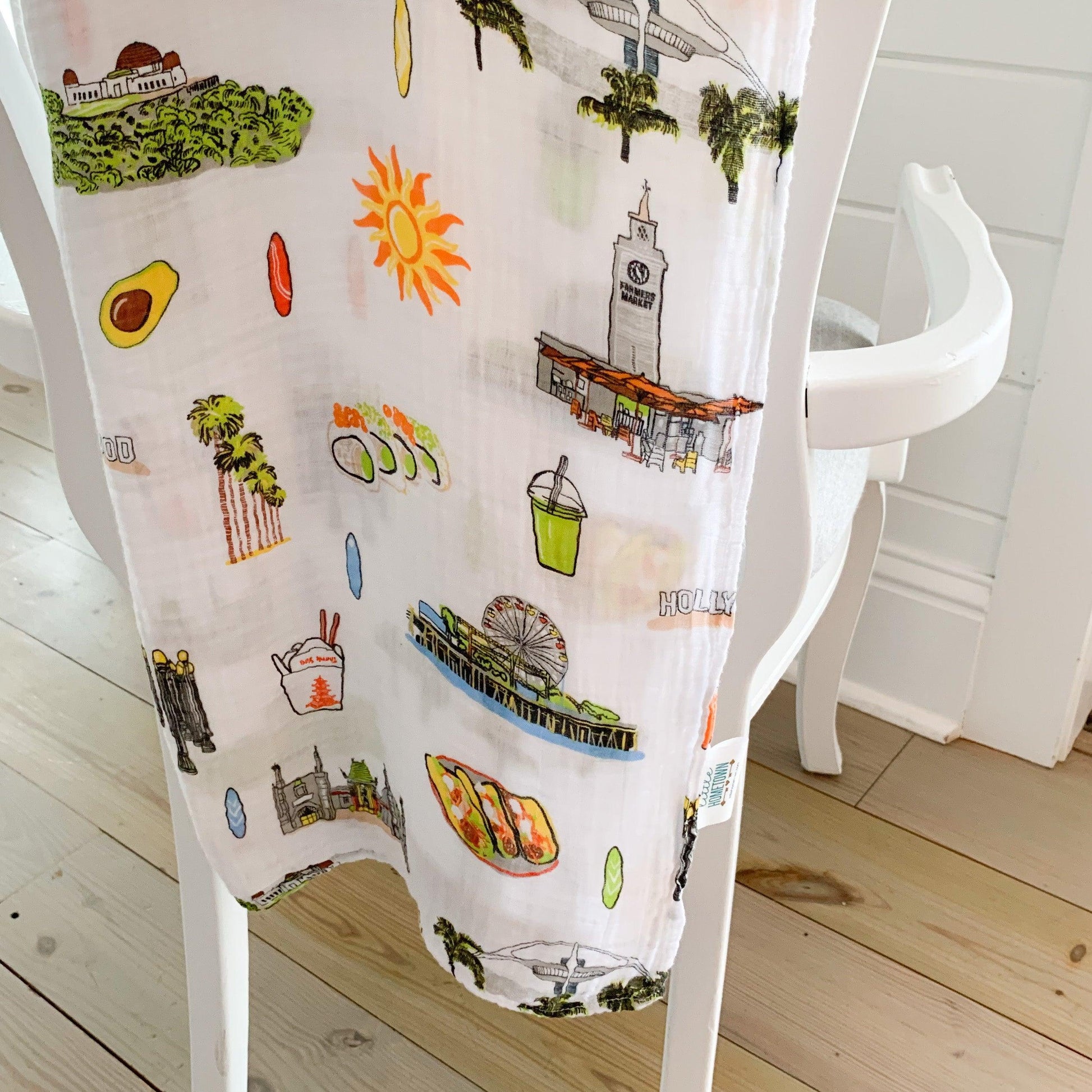 Los Angeles-themed baby muslin swaddle blanket with iconic landmarks and pastel colors, folded neatly.