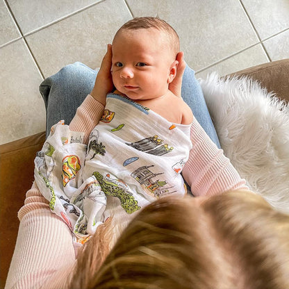 Los Angeles-themed baby muslin swaddle blanket with iconic landmarks and palm trees in soft pastel colors.