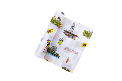 Los Angeles-themed baby muslin swaddle blanket with iconic landmarks and pastel illustrations on a white background.
