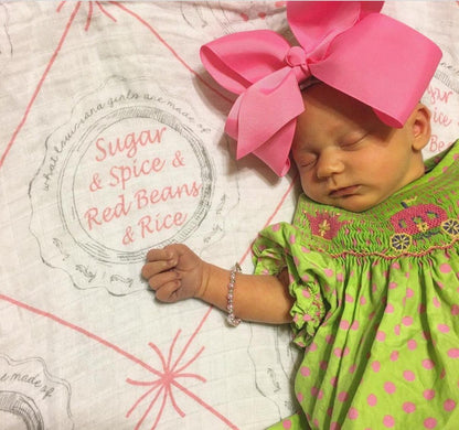 Louisiana-themed baby girl muslin swaddle blanket with pink accents, featuring state icons and "Louisiana" text.