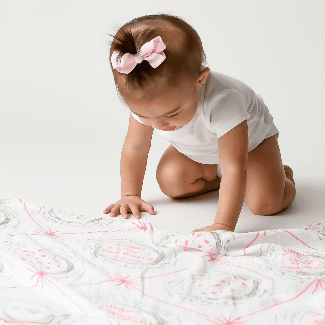 White muslin swaddle blanket with "Louisiana Baby Girl" text and state icons, including a pelican and magnolia.