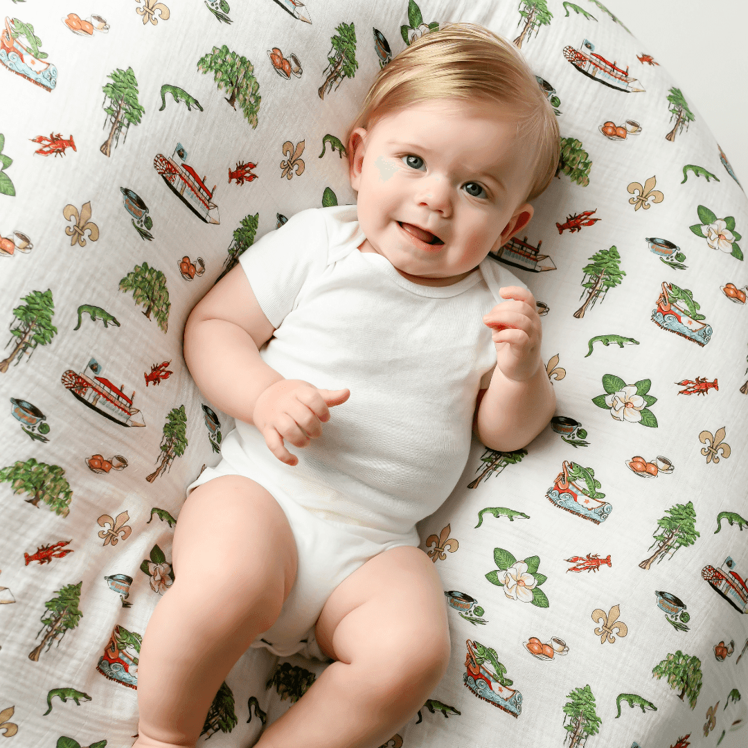 Louisiana-themed baby muslin swaddle blanket featuring state icons like pelicans, magnolias, and crawfish.