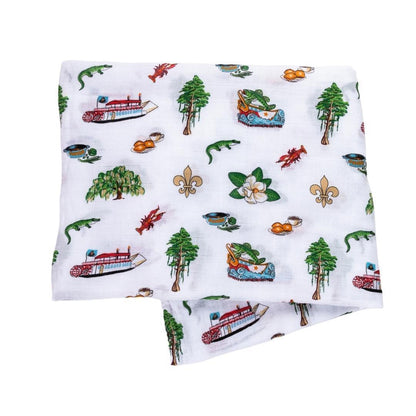 Louisiana-themed baby muslin swaddle with state icons like pelicans, magnolias, and crawfish on a white background.