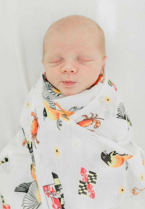 White muslin swaddle blanket with Maryland-themed illustrations, including crabs, flags, and landmarks.
