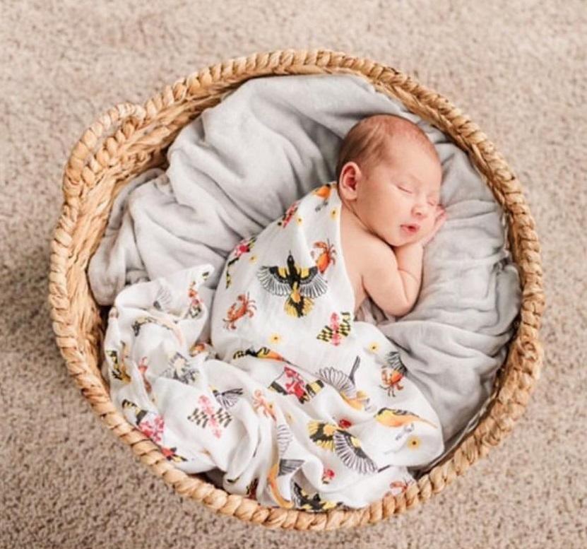 White muslin swaddle blanket with Maryland-themed illustrations, including crabs, lighthouses, and state symbols.