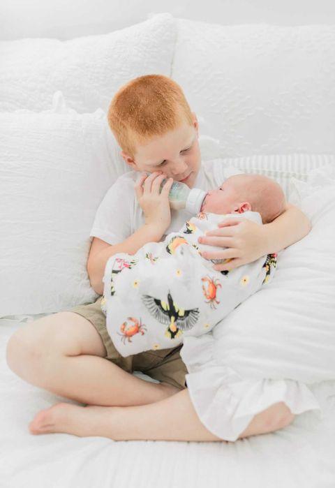 White muslin swaddle blanket with Maryland-themed illustrations, including crabs, lighthouses, and state symbols.