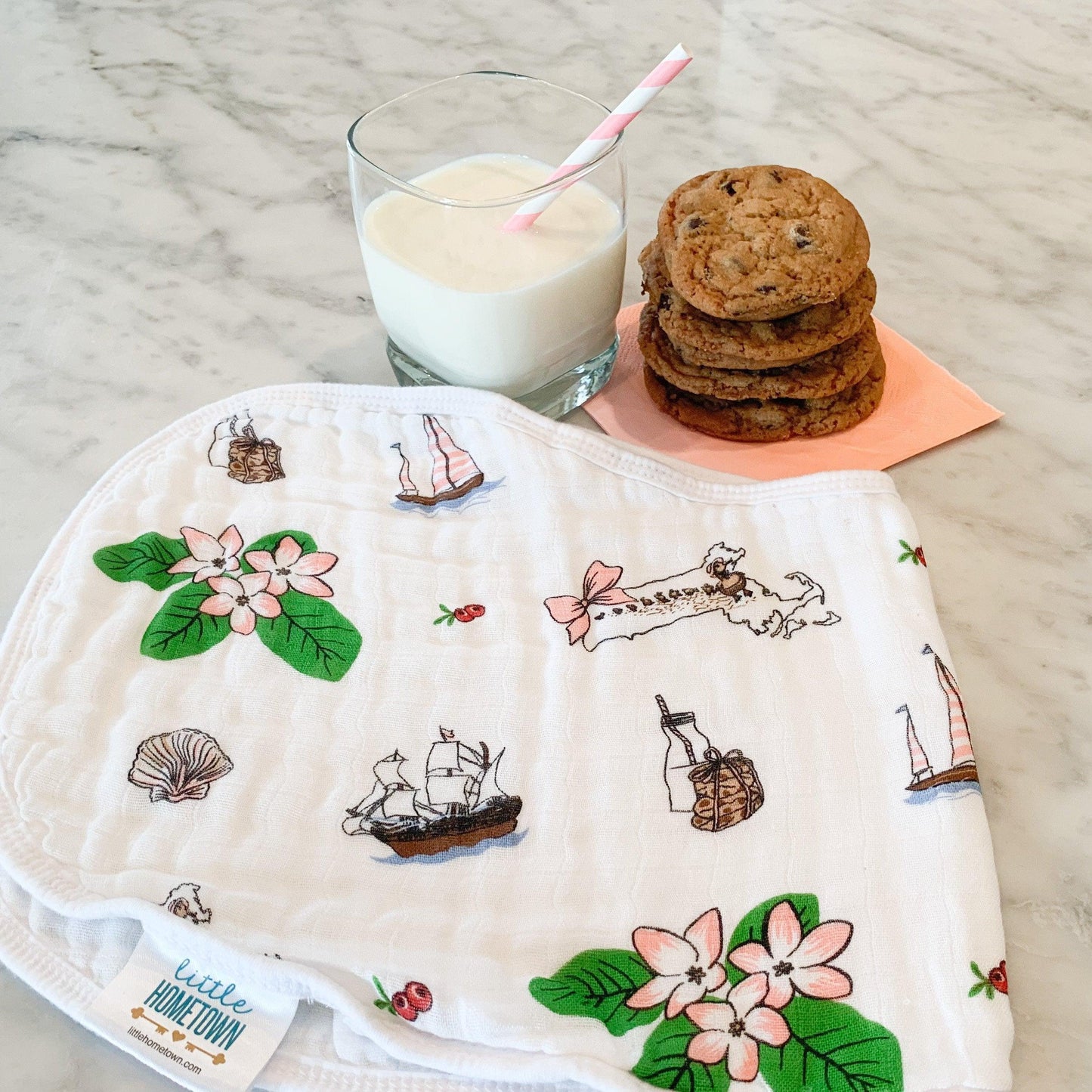 Soft muslin swaddle blanket with a floral pattern featuring Massachusetts state symbols, including the mayflower.