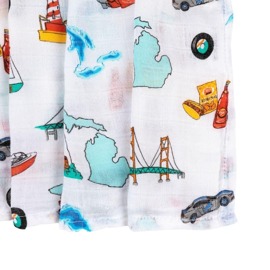White muslin swaddle blanket with blue and yellow Michigan-themed illustrations, including the state outline and landmarks.