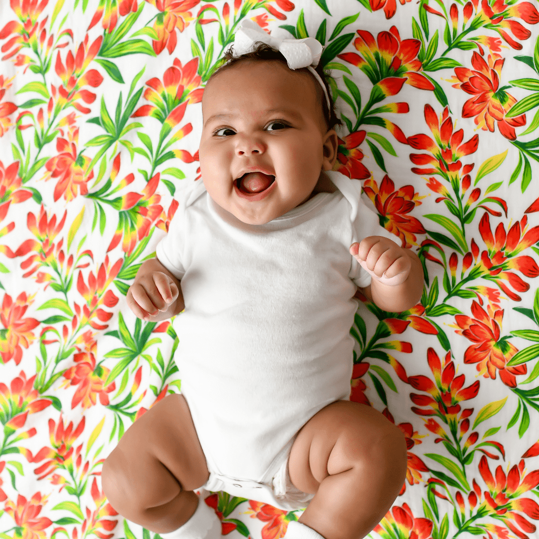 Muslin swaddle baby blanket with a prairie fire design, featuring vibrant red and orange flames on a white background.