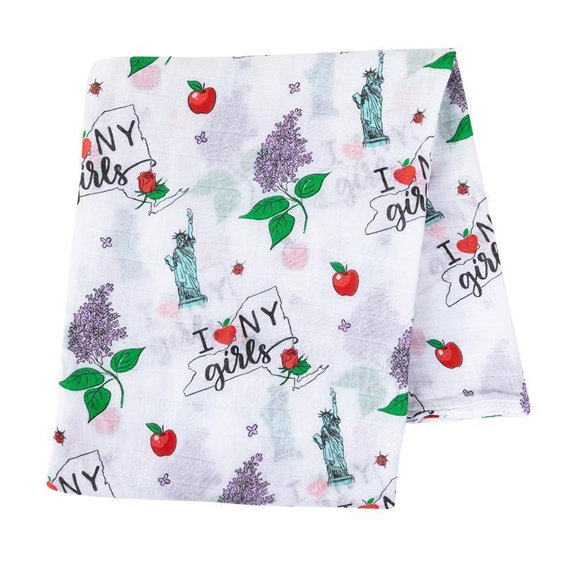 Pink muslin swaddle blanket with New York-themed illustrations, including the Statue of Liberty and yellow taxis.