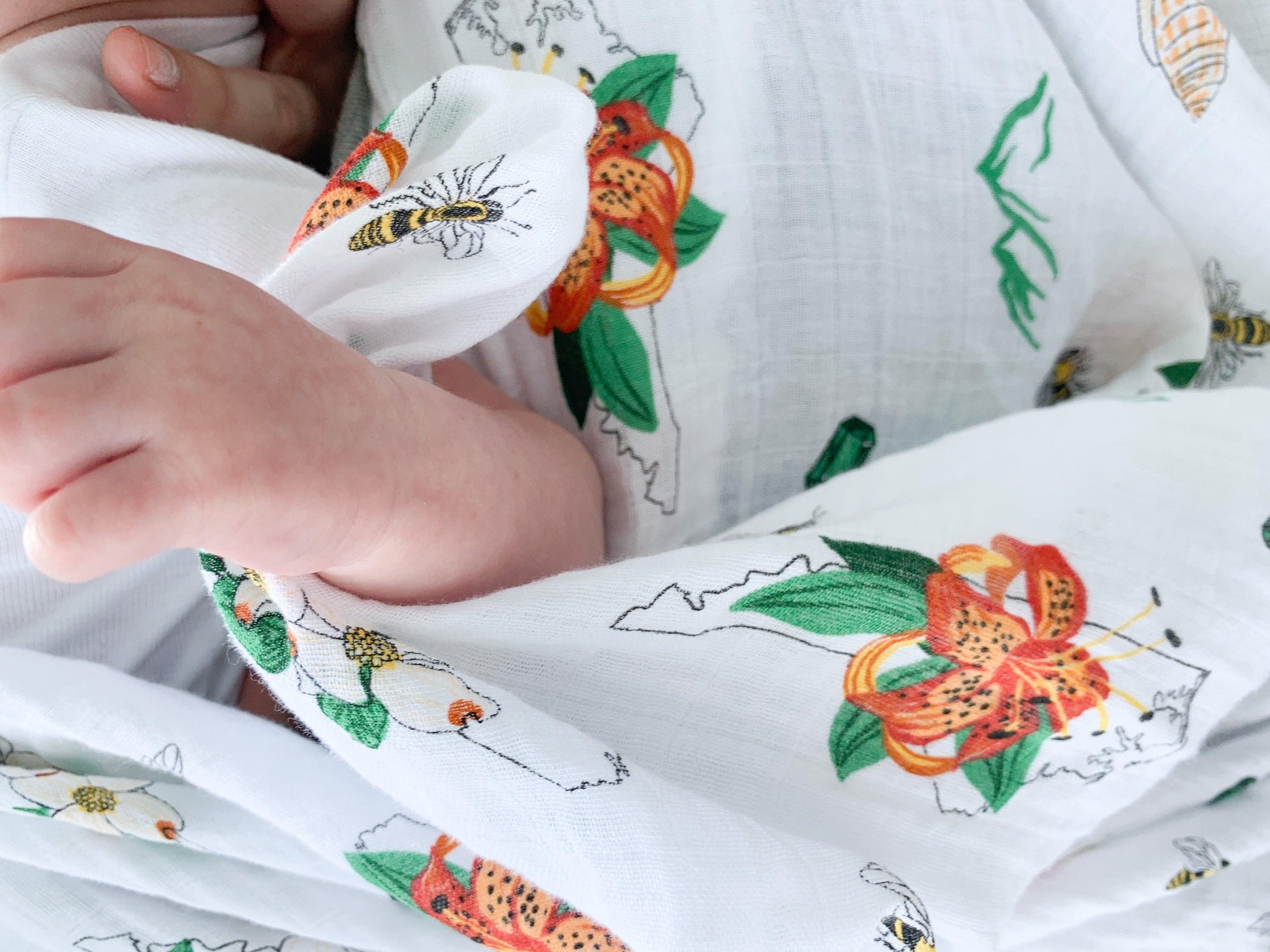 North Carolina-themed baby muslin swaddle blanket with floral design, featuring state symbols and landmarks.