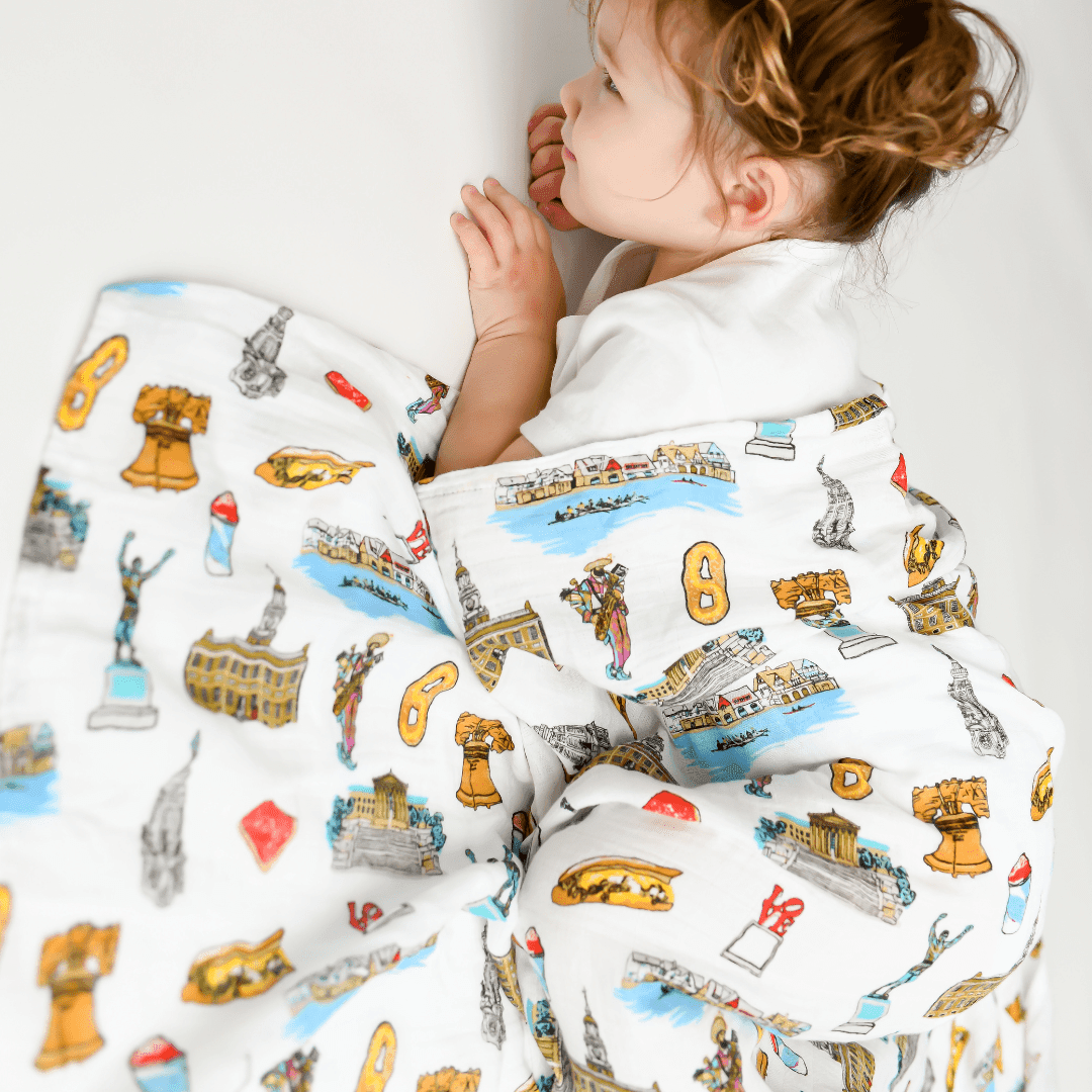 Philadelphia-themed baby muslin swaddle blanket featuring iconic landmarks in soft pastel colors.