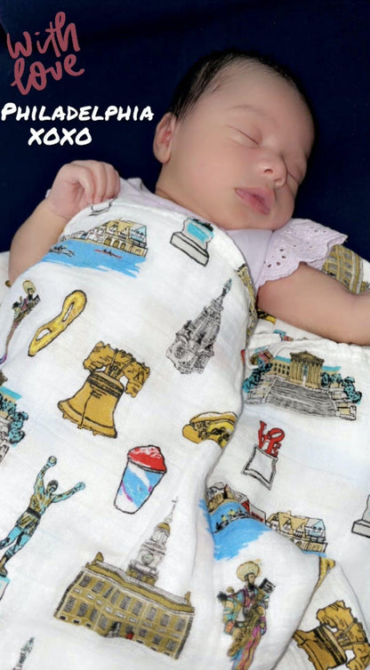 Philadelphia-themed baby muslin swaddle blanket with iconic landmarks in soft pastel colors on a white background.