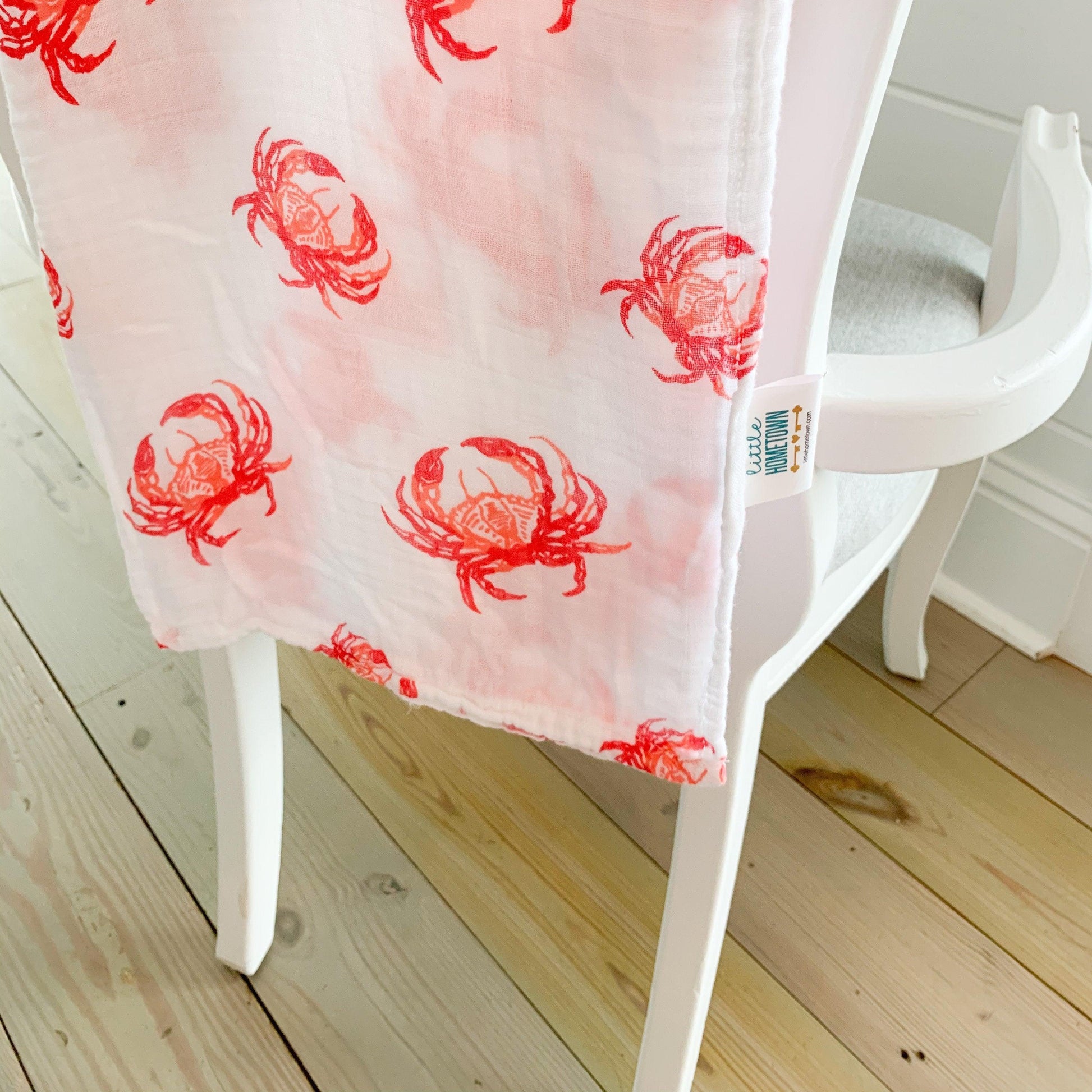 Soft pink muslin swaddle blanket with cute red crab illustrations, perfect for newborns and baby showers.