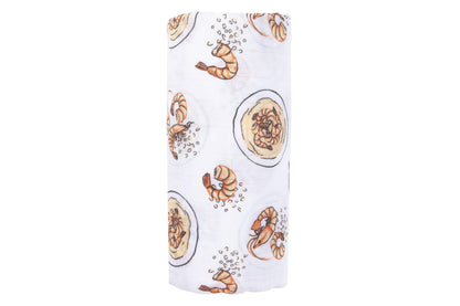 White muslin swaddle blanket with colorful shrimp and grits pattern, featuring bowls, shrimp, and corn.