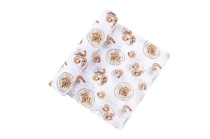 White muslin swaddle blanket with playful shrimp and grits illustrations, featuring vibrant orange and yellow hues.