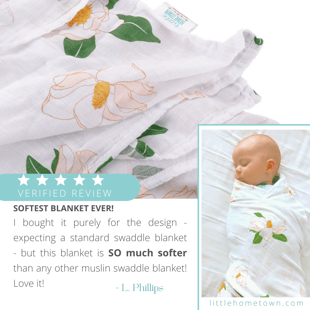 White muslin swaddle blanket with delicate magnolia flower print in soft pink and green hues, folded neatly.