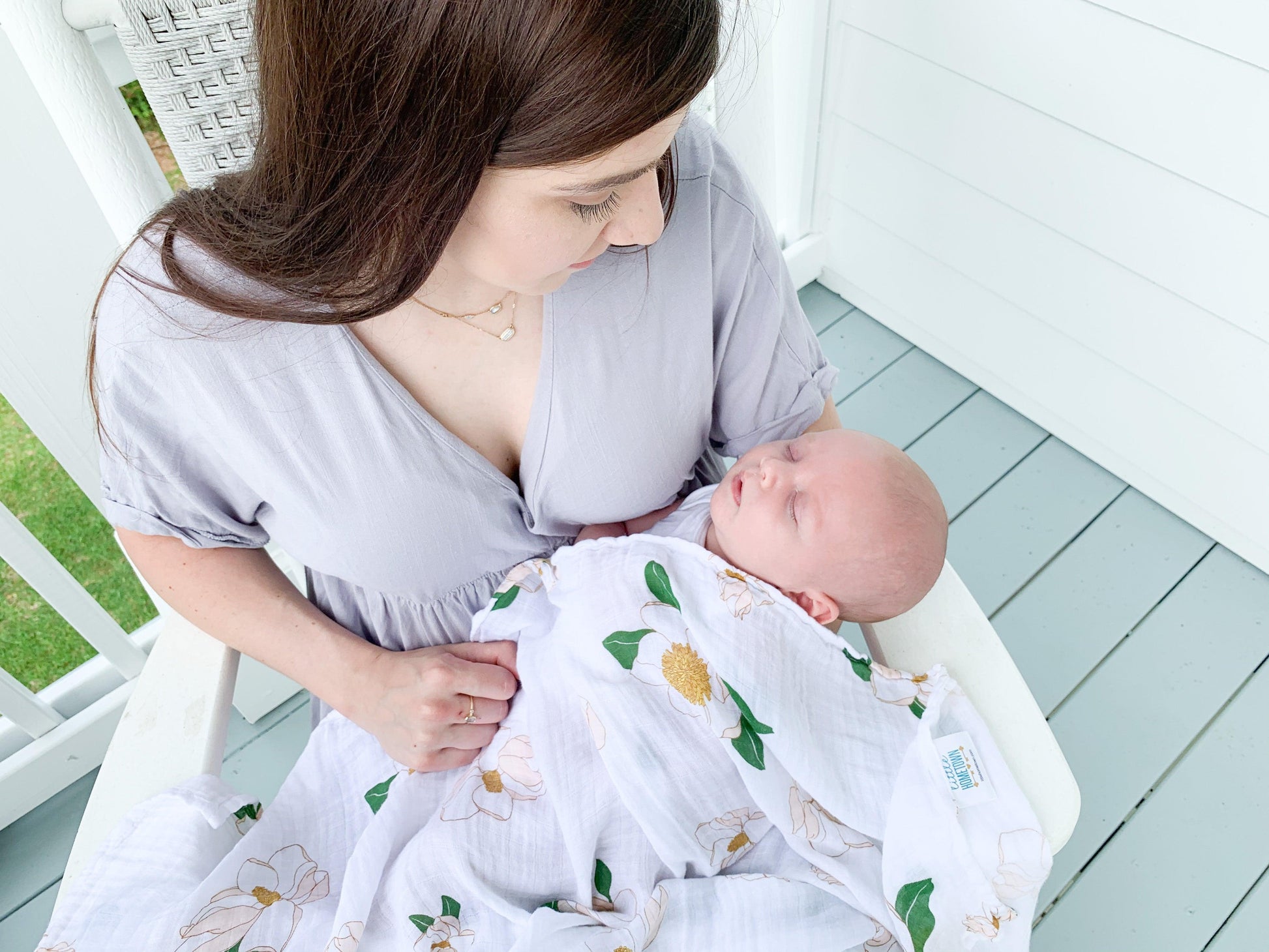 Soft muslin swaddle blanket with delicate Southern Magnolia print, featuring white flowers and green leaves.