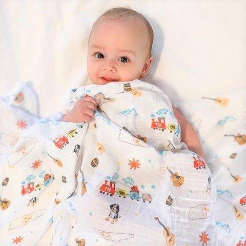 Tennessee-themed baby muslin swaddle blanket with state icons like guitars, horses, and musical notes in soft pastel colors.