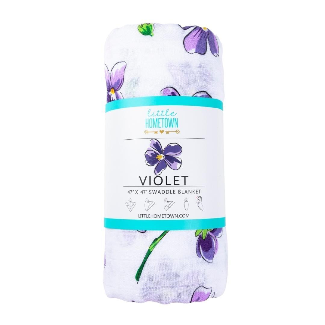 Soft violet muslin swaddle blanket with white floral patterns, neatly folded on a white background.