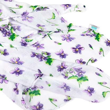 Soft violet muslin swaddle blanket with white floral patterns, neatly folded on a white background.