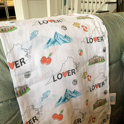 White muslin swaddle blanket with a Virginia state map design, featuring landmarks, animals, and state symbols.