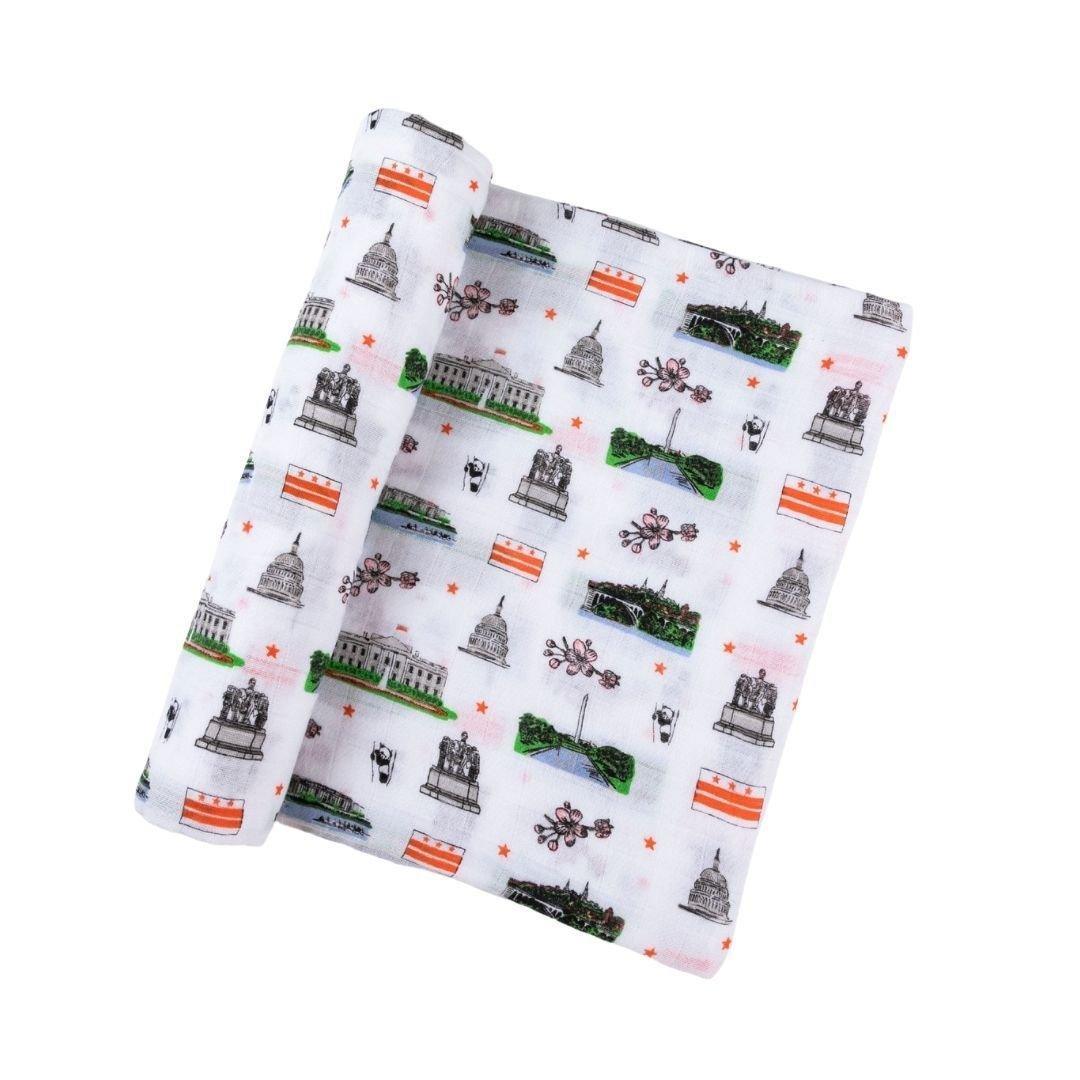 White muslin swaddle blanket with colorful illustrations of Washington D.C. landmarks, including the Capitol and Lincoln Memorial.