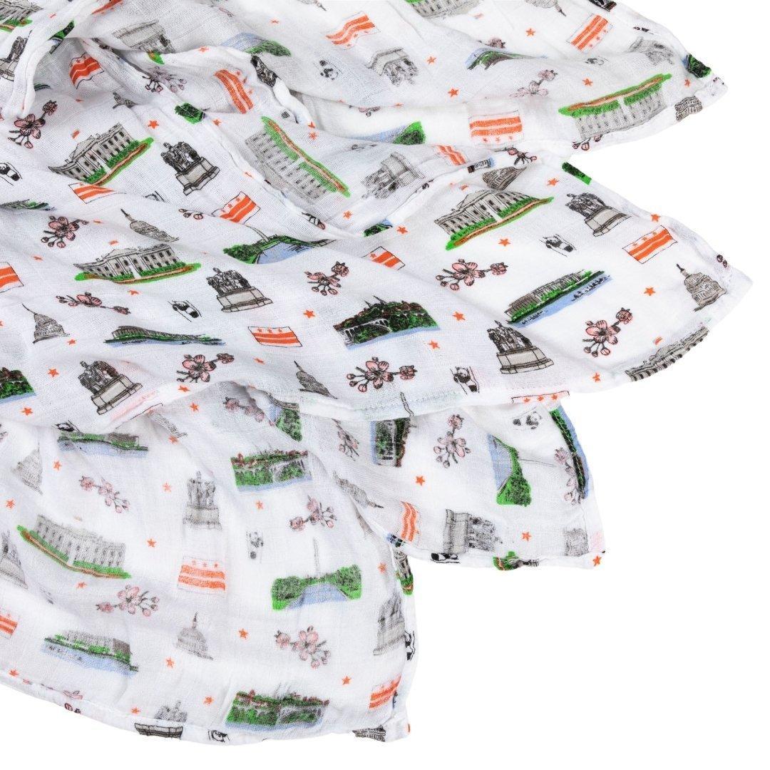 White muslin swaddle blanket featuring colorful illustrations of Washington D.C. landmarks and icons.