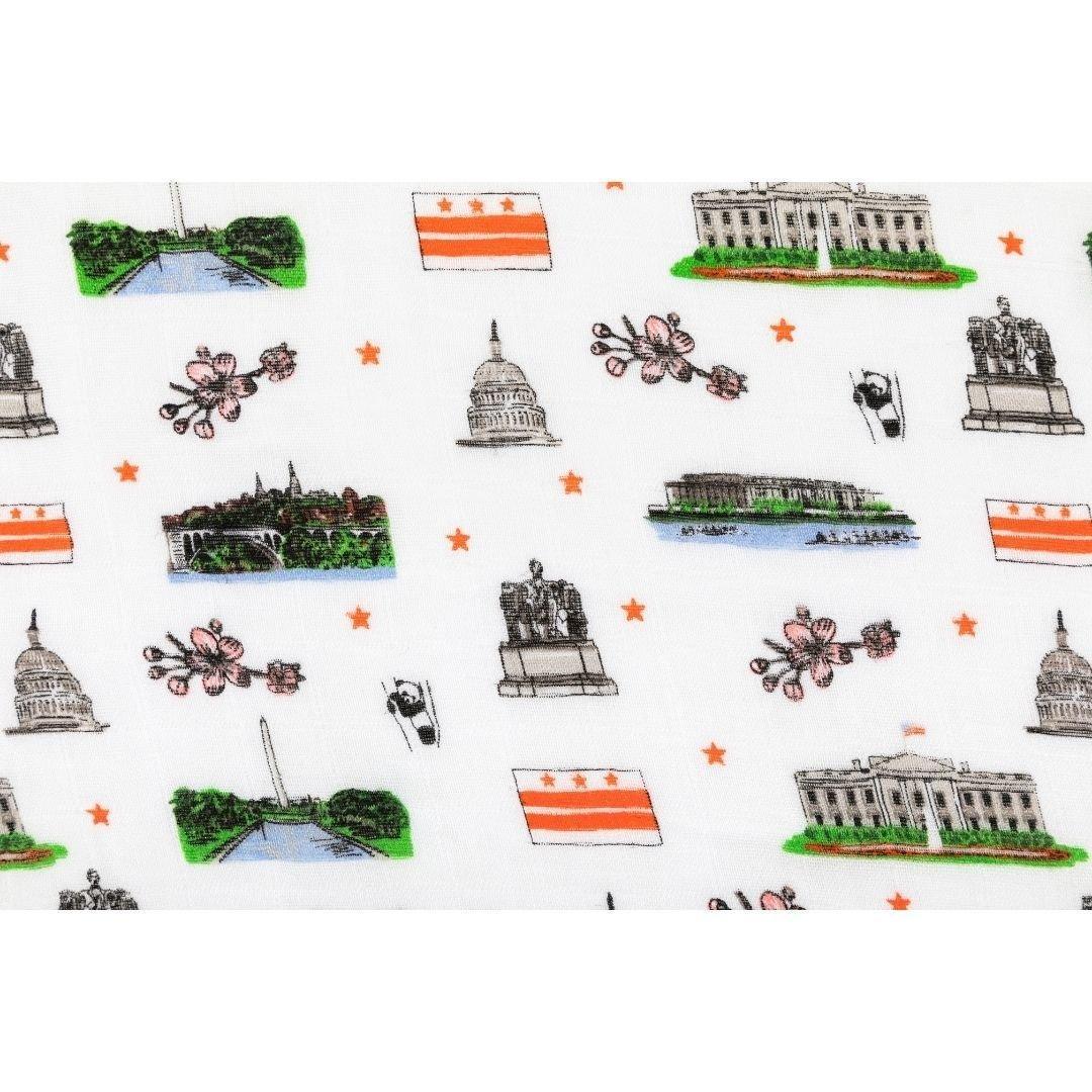 White muslin swaddle blanket featuring colorful illustrations of Washington D.C. landmarks and icons.